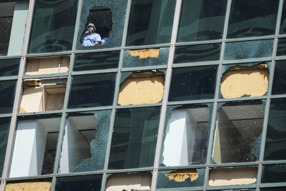 FILE - Workers clean out shattered glass at the Wells Fargo building as clean up from the previous week's storm continues in downtown Houston, Monday, May 20, 2024. (Brett Coomer/Houston Chronicle via AP, file)