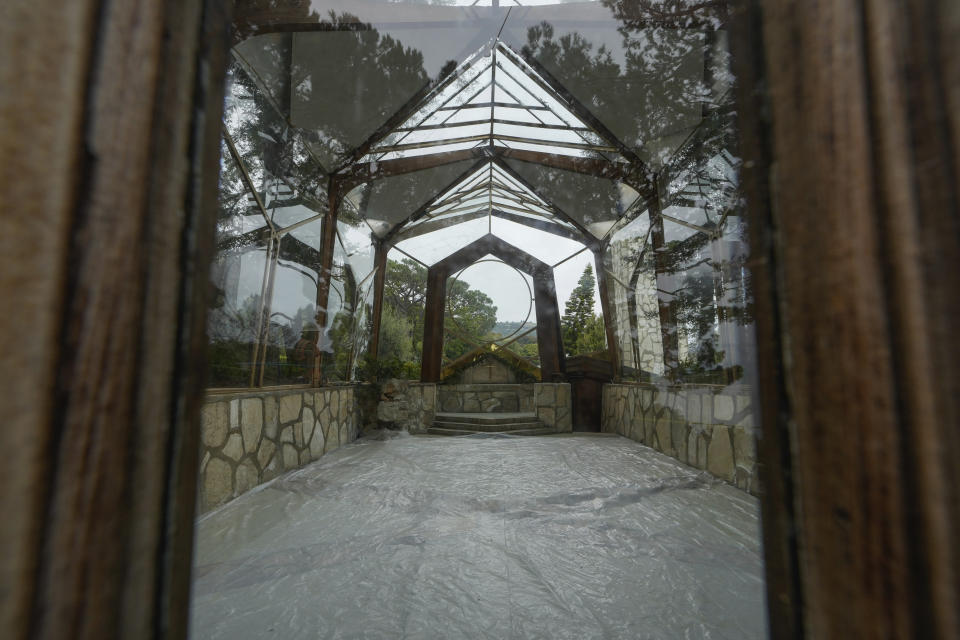 The emptied interior of Wayfarers Chapel, also known as "The Glass Church," is seen through the closed front glass doors in Rancho Palos Verdes, Calif., Wednesday, May 15, 2024. The modernist chapel, which is presently closed due to the accelerated land movements, features organic architecture with glass walls in a redwood grove overlooking the Pacific Ocean. The Wayfarers Chapel glass structure, triangular designs, and a transparent glass roof that bathes the interior in natural light was designed by architect Lloyd Wright, son of Frank Lloyd Wright, and completed in 1951. Wayfarers Chapel management announced plans to disassemble the iconic structure to save it from landslide destruction. (AP Photo/Damian Dovarganes)