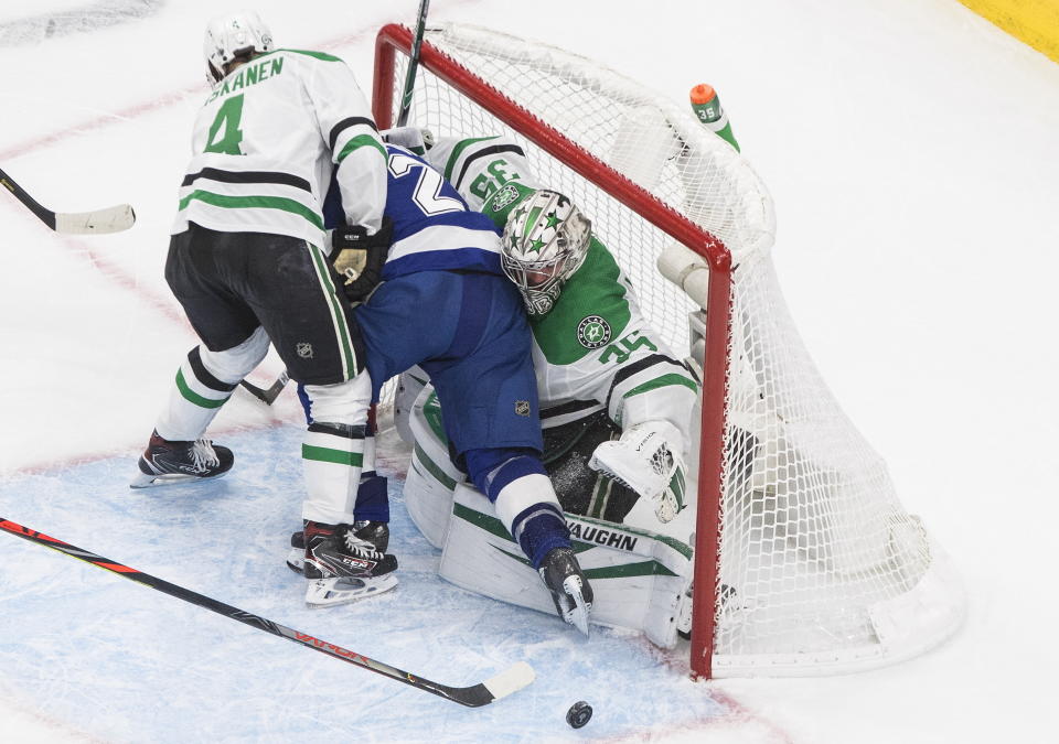 Dallas Stars goaltender Anton Khudobin (35) makes a save as Tampa Bay Lightning center Brayden Point (21) and Stars defenseman Miro Heiskanen (4) crash into the net during the first overtime in Game 5 of the NHL hockey Stanley Cup Final, Saturday, Sept. 26, 2020, in Edmonton, Alberta. (Jason Franson/The Canadian Press via AP)