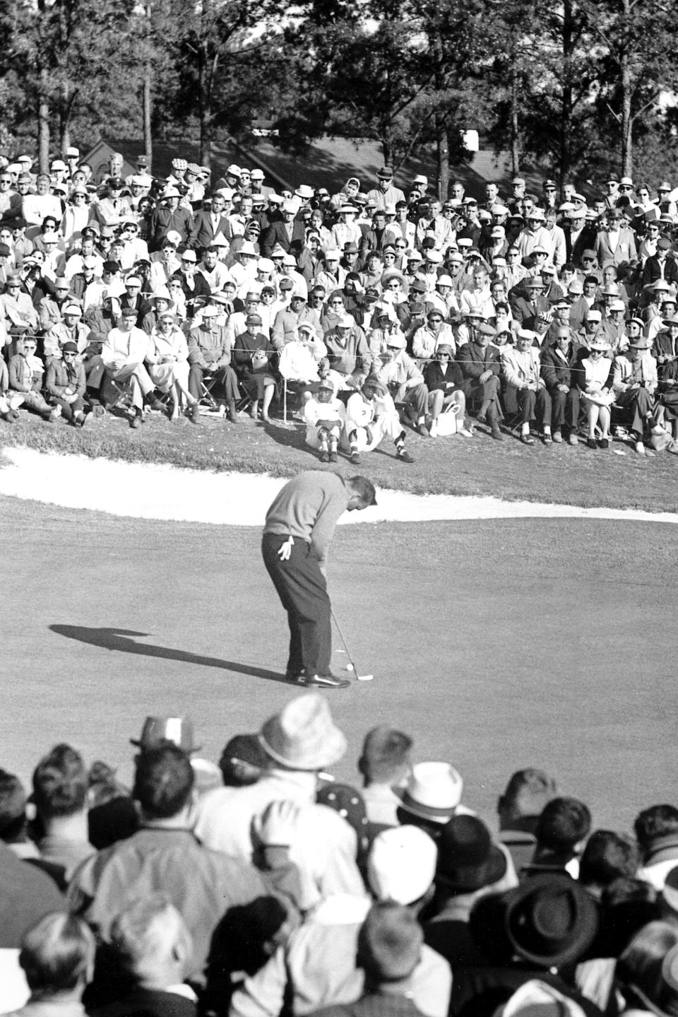 FILE - In this April 10, 1960, file photo, Arnold Palmer makes his final putt before his victory at the Masters Golf Tournament in Augusta, Ga. There is no Masters this year because of the COVID-19 pandemic, the first time there is no golf at Augusta National the first full week in April since the end of World War II in 1945. (AP Photo/File)