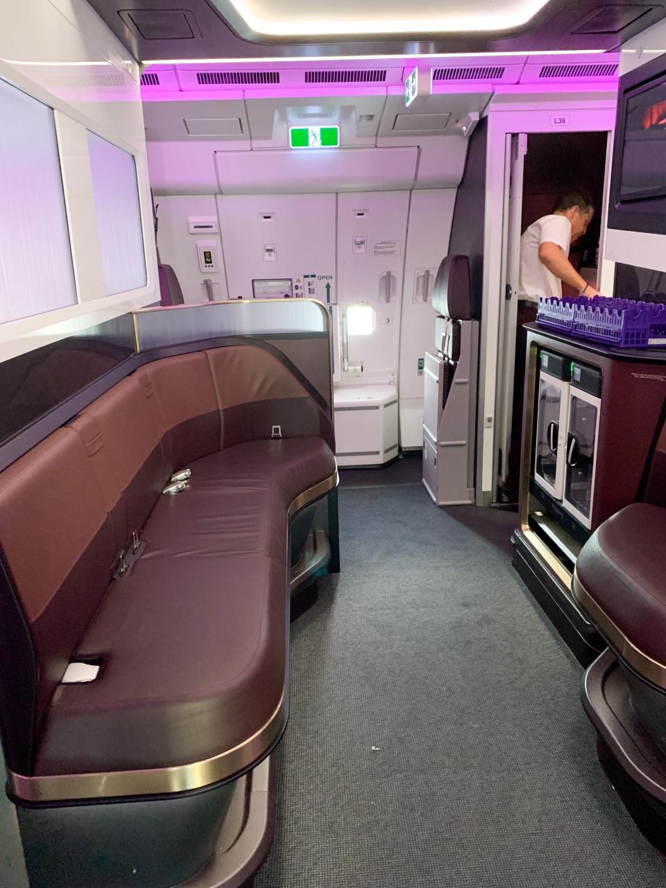 A small, in-flight lounge with a leather sofa and minibar
