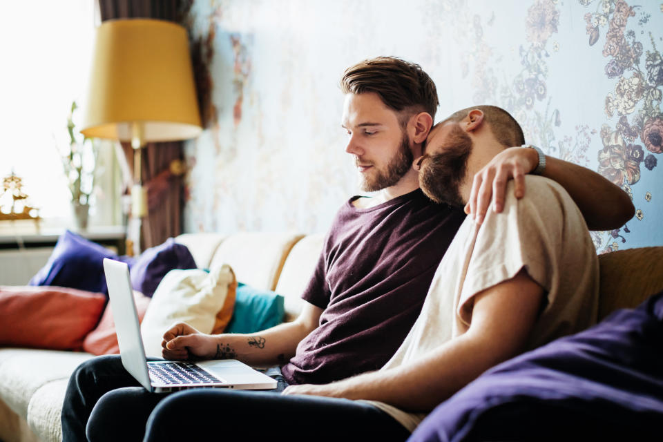 Two men embracing on sofa. (Getty Images)