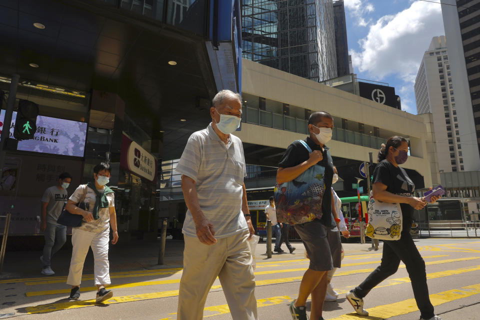 People wearing face masks to prevent the spread of coronavirus walk on a downtown street in Hong Kong, Tuesday, Aug. 17, 2021. Hong Kong will tighten entry restrictions for travelers arriving from the United States and 14 other countries from Friday, increasing the quarantine period to 21 days. (AP Photo/Vincent Yu)