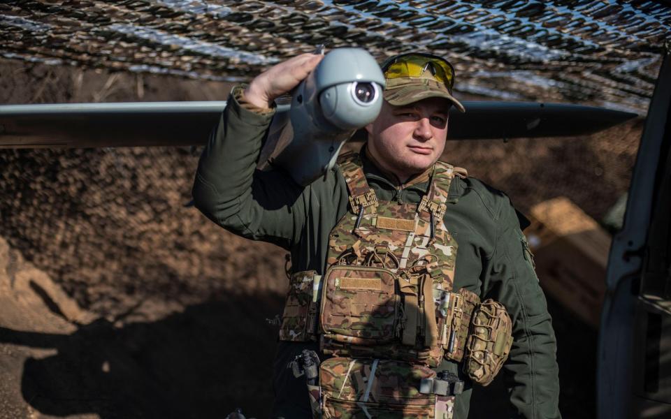 A member of a Ukrainian reconnaissance drone unit from the 80th Air Assault Brigade poses for a portrait with a drone at a position in Donbas