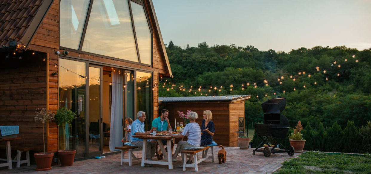 Three generation family having a garden party in the summer. They are sitting at the dining table in the backyard and having dinner