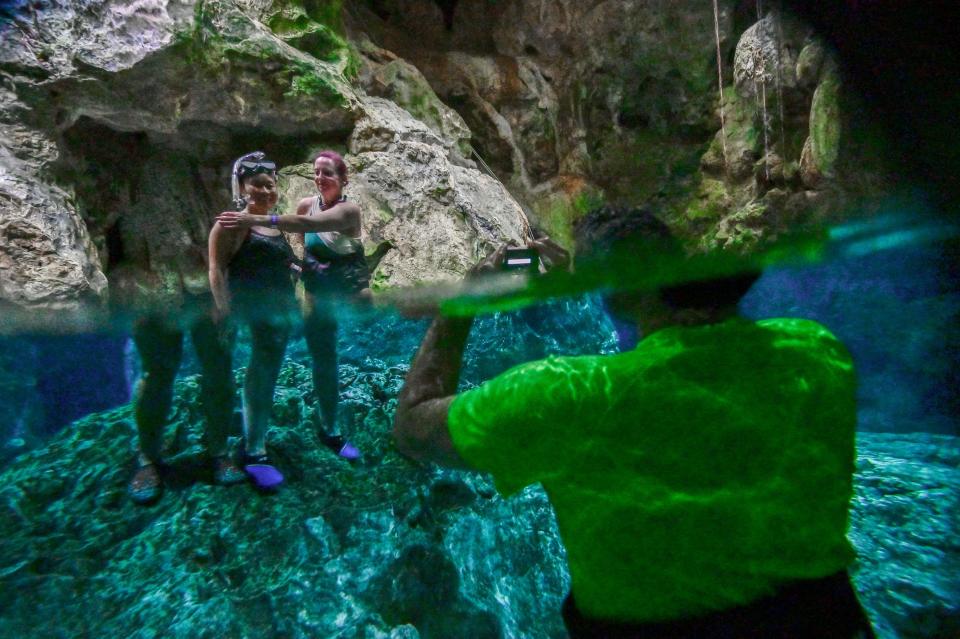 Tourists pose for a picture in a water-filled sinkhole known as cenote at Aktun Chen natural park, near the construction site of Section 5 South of the Mayan Train between the resorts of Playa del Carmen and Tulum which was halted by a district judge pending resolution of an injunction sought by scuba divers and environmentalists -- in Akumal, Tulum, Quintana Roo State, Mexico, on April 27, 2022. - A Mexican judge earlier this month suspended construction of part of President Andres Manuel Lopez Obrador's flagship tourist train project in the Yucatan peninsula due to a lack of environmental impact studies. The Mayan Train, a roughly 1,500-kilometre (950 mile) rail loop linking popular Caribbean beach resorts and archeological ruins, has met with opposition from environmentalists and indigenous communities. (Photo by Pedro PARDO / AFP) (Photo by PEDRO PARDO/AFP via Getty Images)