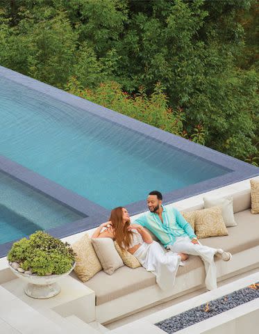 <p>Yoshihiro Makino/Architectural Digest</p> Chrissy Teigen and John Legend pose by their pool.