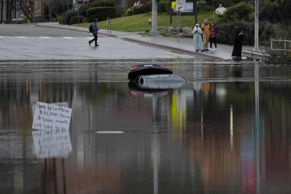 A car sits partially submerged on a flooded road during a rain storm Monday, Jan. 22, 2024, in San Diego. Heavy rainfall around the U.S. on Monday prompted first responders in Texas to conduct water rescues and officials in California to issue evacuation warnings over potential mud slides in parts of Los Angeles County. (AP Photo/Gregory Bull)