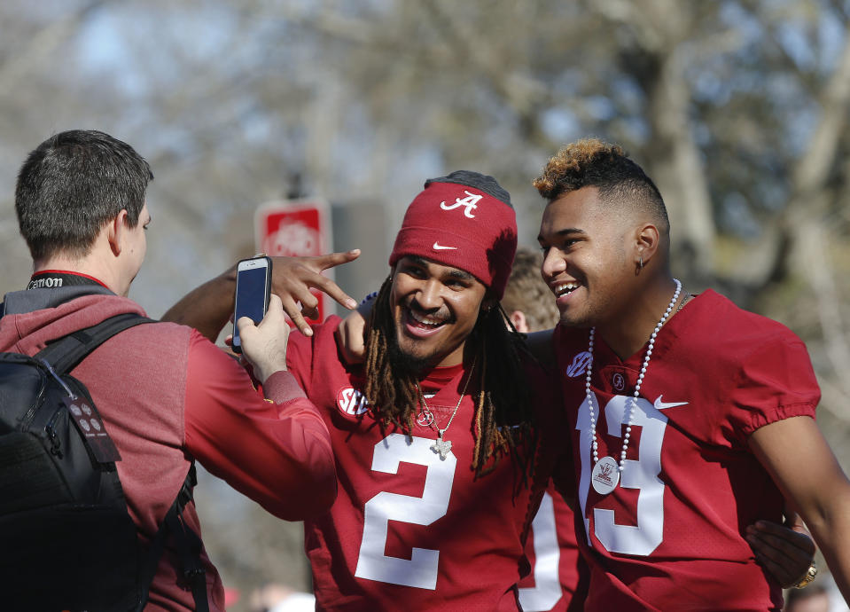 FILE - Alabama quarterbacks Jalen Hurts, center, and Tua Tagovailoa have their picture taken during the NCAA college football national championship parade, Saturday, Jan. 20, 2018, in Tuscaloosa, Ala. The QBs who go head-to-head for the first time in the NFL when the Miami Dolphins visit the Philadelphia Eagles on Sunday, will forever be linked by their tenures under coach Nick Saban at Alabama. (AP Photo/Brynn Anderson)