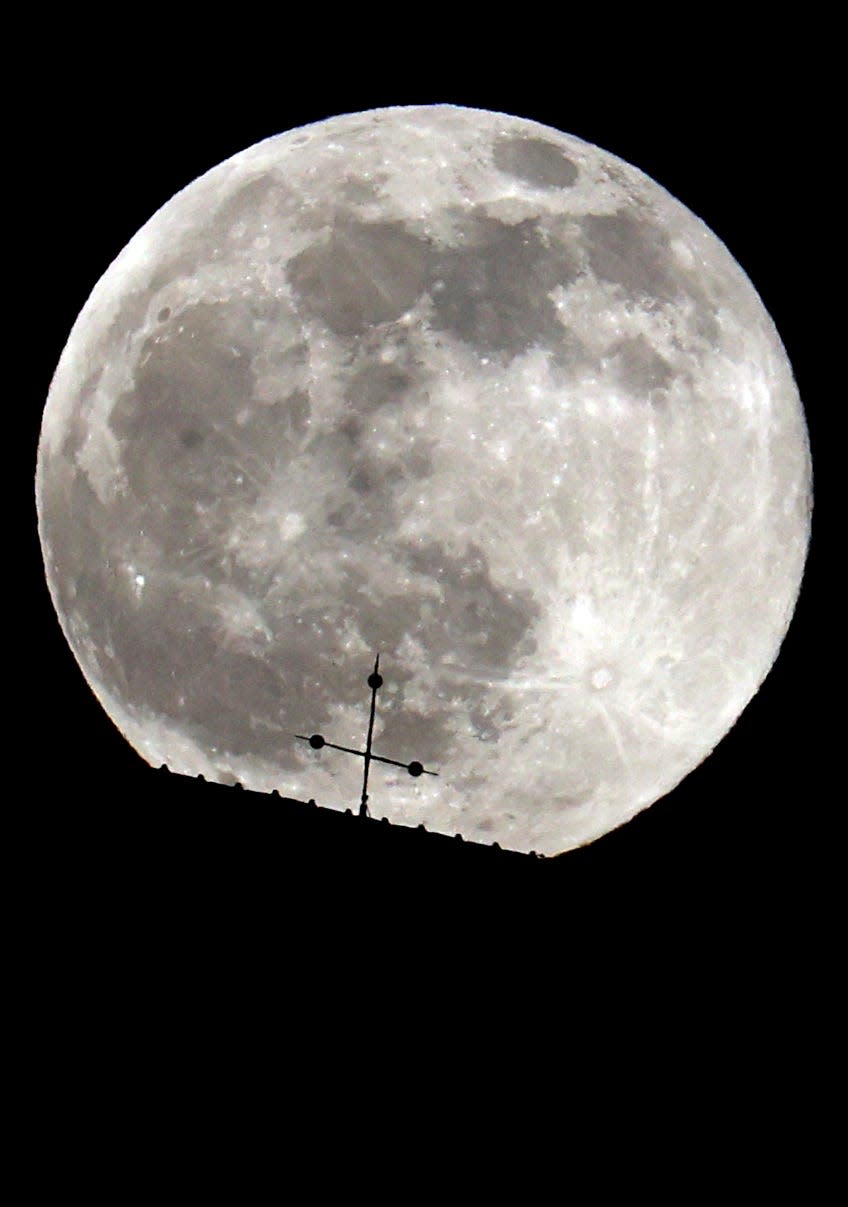 The full moon can be seen behind the steeple of St. George's Church on April 16 in Bernbeuren, Germany.