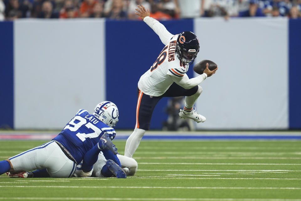 Chicago Bears quarterback Caleb Williams (18) scrambles under pressure from Indianapolis Colts defensive end Laiatu Latu (97) and linebacker Zaire Franklin (44) during the first half of an NFL football game Sunday, Sept. 22, 2024, in Indianapolis. (AP Photo/Michael Conroy)