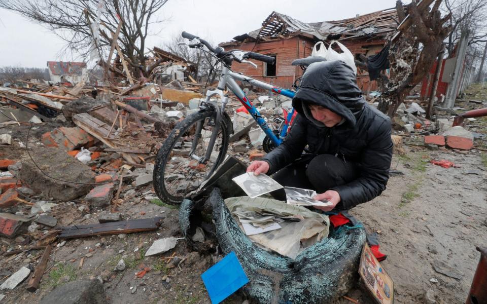 A local woman looks over family photos which she found in the debris of her shelled house on the outskirt of Chernihiv city, Ukraine - SERGEY DOLZHENKO/EPA-EFE/Shutterstock