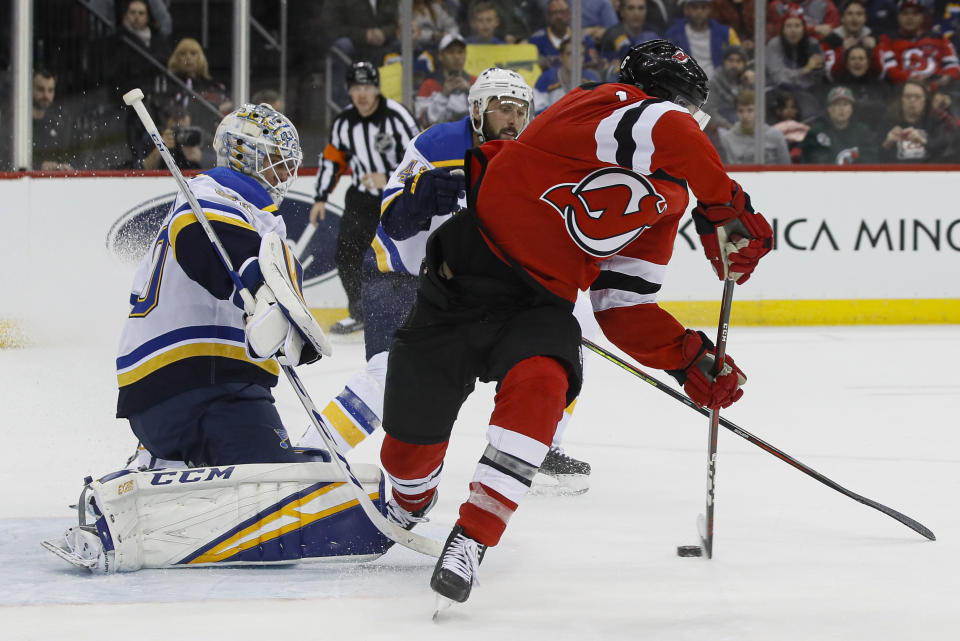 New Jersey Devils center Kevin Rooney, right, puts the puck into the net against St. Louis Blues goaltender Jordan Binnington, left, before the goal was disallowed for interference during the second period of an NHL hockey game, Friday, March 6, 2020, in Newark. (AP Photo/John Minchillo)