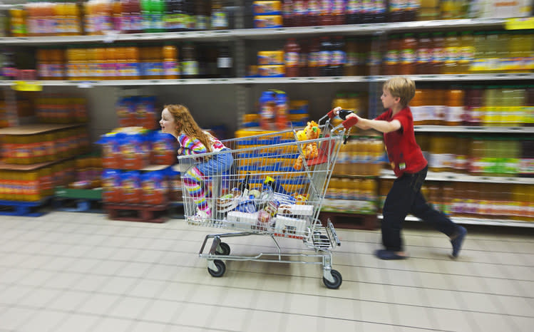 A kid pushing another kid in a cart