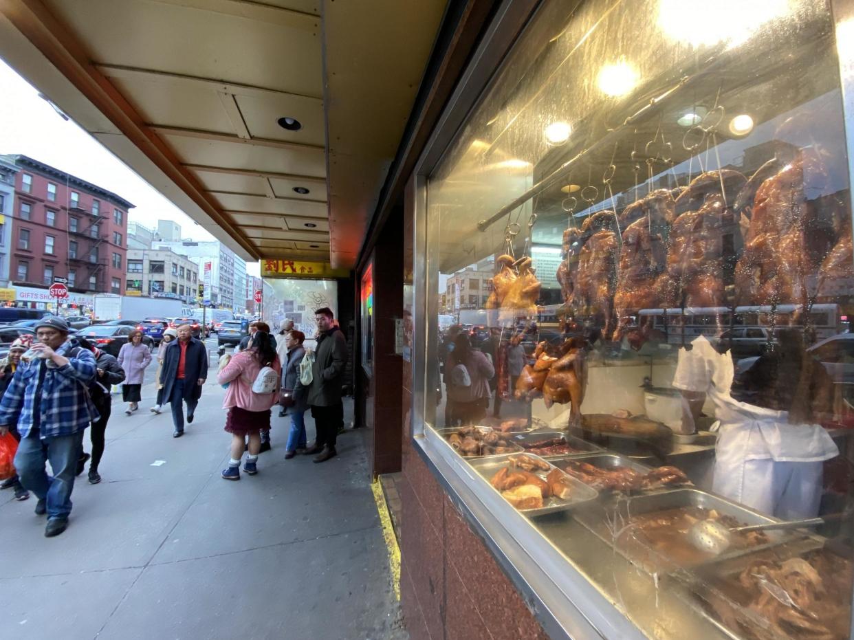 Pedestrians walk by Peking ducks in a Chinatown restaurant's window: Clark Mindock/The Independent