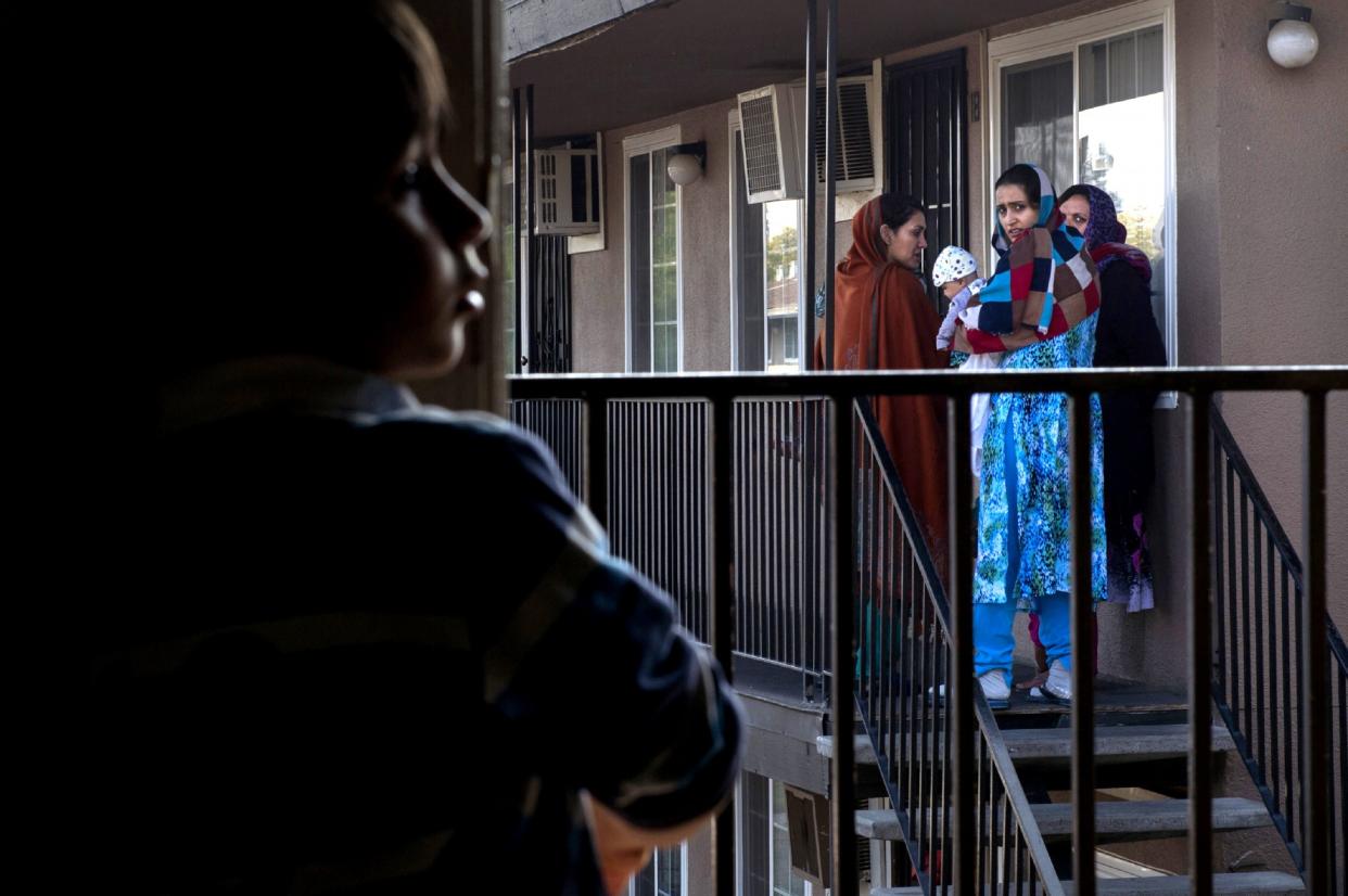 Malalai Rafi, far right, joins other Afghan women to bid good-bye to Mohammad Eltaf Stana, 5 ½, left, and his family as they move from Skyview Villa Apartments on Mon. Nov. 23, 2015. Mohammad's mother had been hit by a car while walking his sister home from school along Edison Avenue, the same street Malalai’s husband was killed and son severely injured when a motorist hit them. Mohammad's family did not feel safe living in the complex. Many of the Afghan women who fled the Taliban with their SIV husbands rely heavily on one another. They feel isolated, most are unable to speak English, cannot drive and have small children they can’t afford daycare for. (Photograph by Renée C. Byer/The Sacramento Bee)