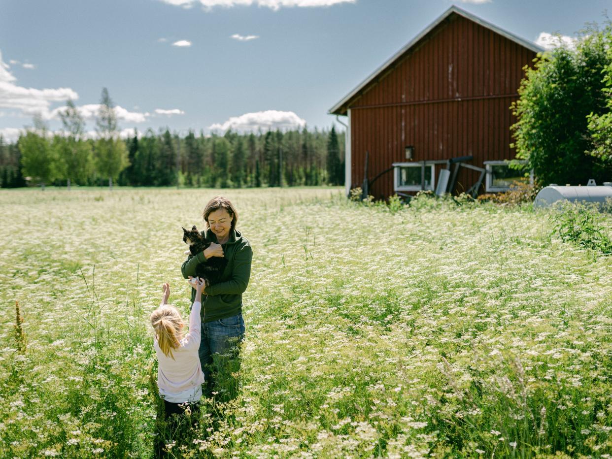 Girl taking cat from mother while standing on field