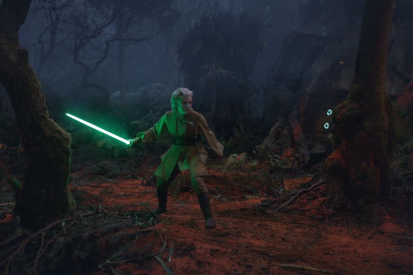 Jedi Padawan Jecki holding a green light saber while standing in the wilderness in episode five of The Acolyte