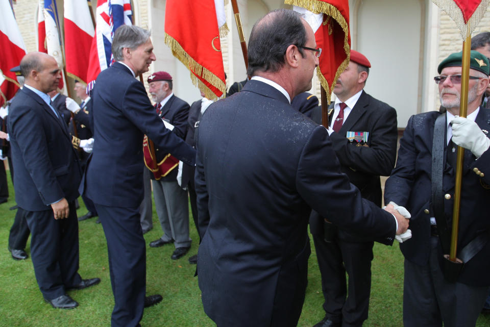 French President Francois Hollande, right, and Bristish Minister of Defense Philippe Hammond shake hands with WWII veterans during a ceremony commemorating the 68th anniversary of the D-Day invasion of France began in 1944, in the British war cemetery of Ranville, western France, Wednesday, June 6, 2012. (AP Photo/David Vincent, Pool)