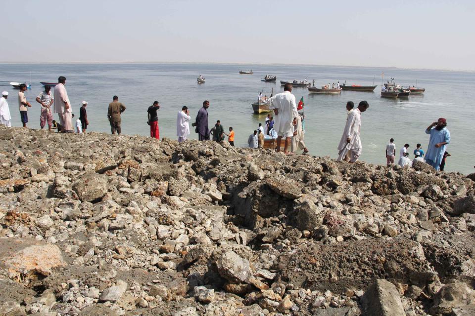 People who arrived by boat stand on an island that rose from the sea following an earthquake, off Pakistan's Gwadar coastline in the Arabian Sea