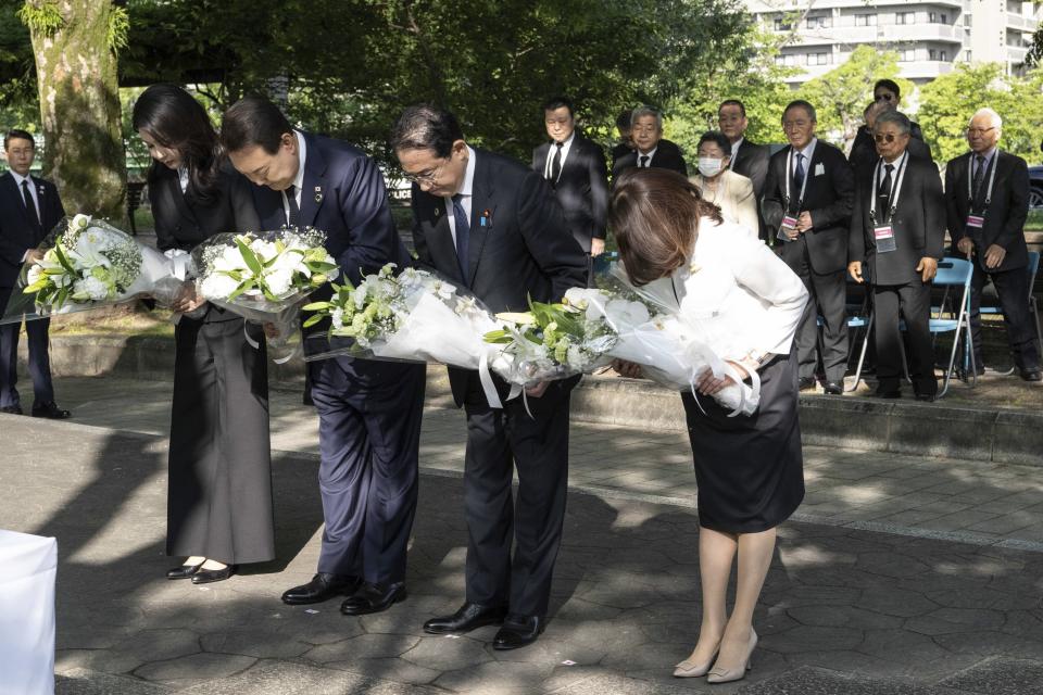 South Korea's President Yoon Suk Yeol, center left, his wife Kim Keon Hee, left, Japan's Prime Minister Fumio Kishida and his wife Yuko Kishida bow as they lay flowers at the Monument in Memory of the Korean Victims of the A-bomb near the Peace Park Memorial in Hiroshima, western Japan Sunday, May 21, 2023, on the sidelines of the G7 Summit Leaders' Meeting. (Yuichi Yamazaki/Pool Photo via AP)