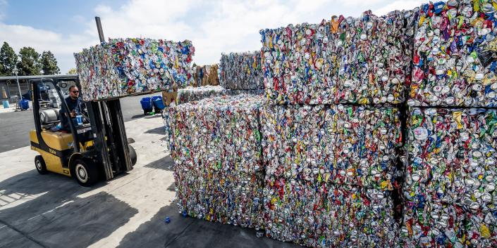 forklift lifting cans that have been condensed into big blocks