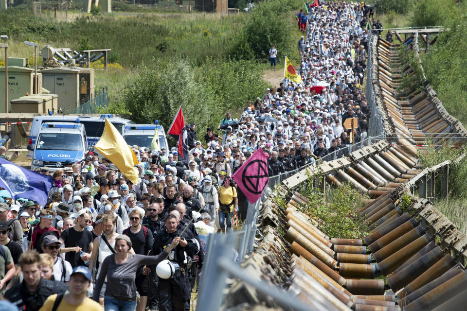 Numerous environmental activists walk on a roadway on the site of the Garzweiler open-cast mine in Garzweiler, Germany, Saturday, June 22, 2019. The protests for more climate protection in the Rhineland continue. (Marcel Kusch/dpa via AP)