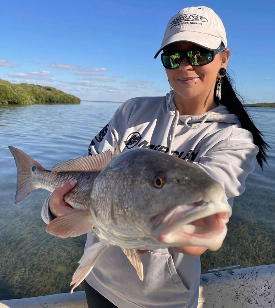 Lindsay Collums of Crystal River shows off a slot size redfish she caught while fishing in Crystal River with Capt. Marrio Castello, of Tall Tales Charters on Wednesday.