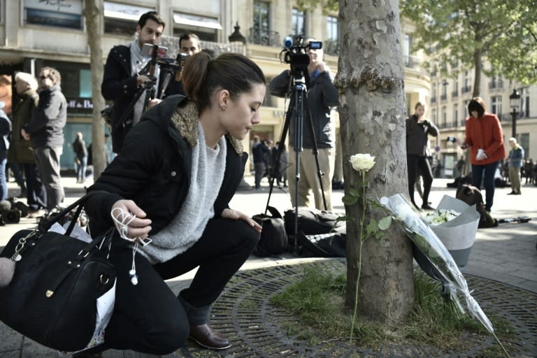 A woman places a flower at the spot on the Champs Elysees in Paris where a gunman killed a police officer and wounded two others