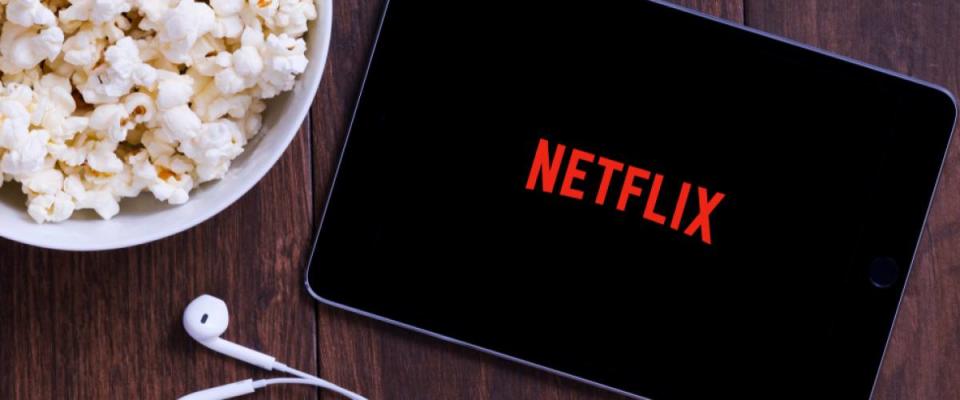 Table with popcorn bottle and Netflix logo on Apple Ipad mini and earphone. Netflix is a global provider of streaming movies and TV series.