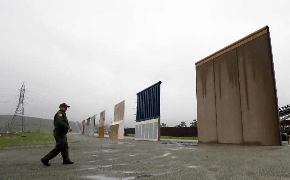 FILE - In this Feb. 5, 2019 file photo a Border Patrol agent walks towards prototypes for a border wall in San Diego. The Trump administration on Wednesday, Feb. 27 plans to demolish eight prototypes of the president's prized border wall that the government built near San Diego one year ago. (AP Photo/Gregory Bull,File)