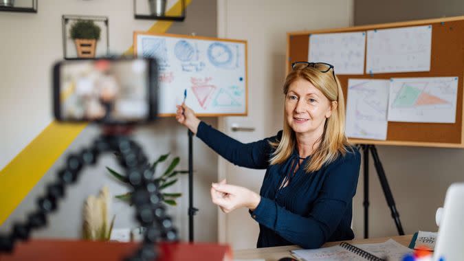 Mature smart professor holding online class for e-learning school kids and students.