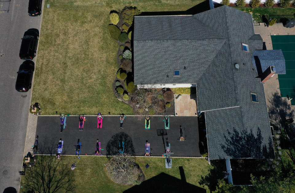 In Long Island, New York, a fitness instructor leads an exercise class in her driveway. She is an instructor at three gyms in her area but they are closed due to the coronavirus pandemic. (Photo by Al Bello/Getty Images)