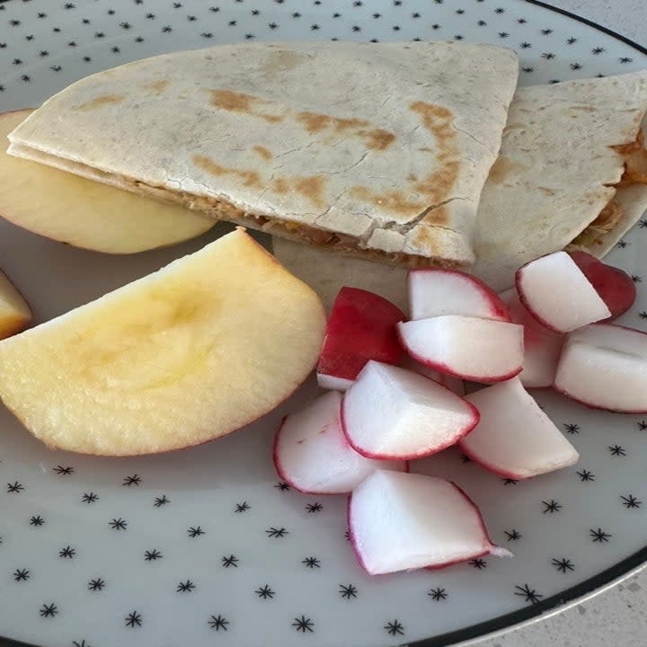 a quesadilla, apple, and radishes on a plate