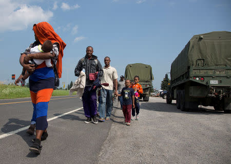 A group of asylum seekers walk down the street as they are escorted from their tent encampment to be processed at Canada Border Services in Lacolle, Quebec, Canada August 11, 2017. REUTERS/Christinne Muschi