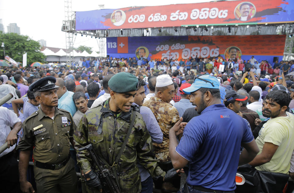 Sri Lankan police officers try to control supporters of Sri Lankan president Maithripala Sirisena and his newly appointed prime minister Mahinda Rajapaksa during a rally held out side the parliamentary complex in Colombo, Sri Lanka, Monday, Nov. 5, 2018. Thousands of Sri Lankans marched Monday in support of a new government led by the country's former strongman, highlighting the political polarization in the Indian Ocean island nation. (AP Photo/Eranga Jayawardena)