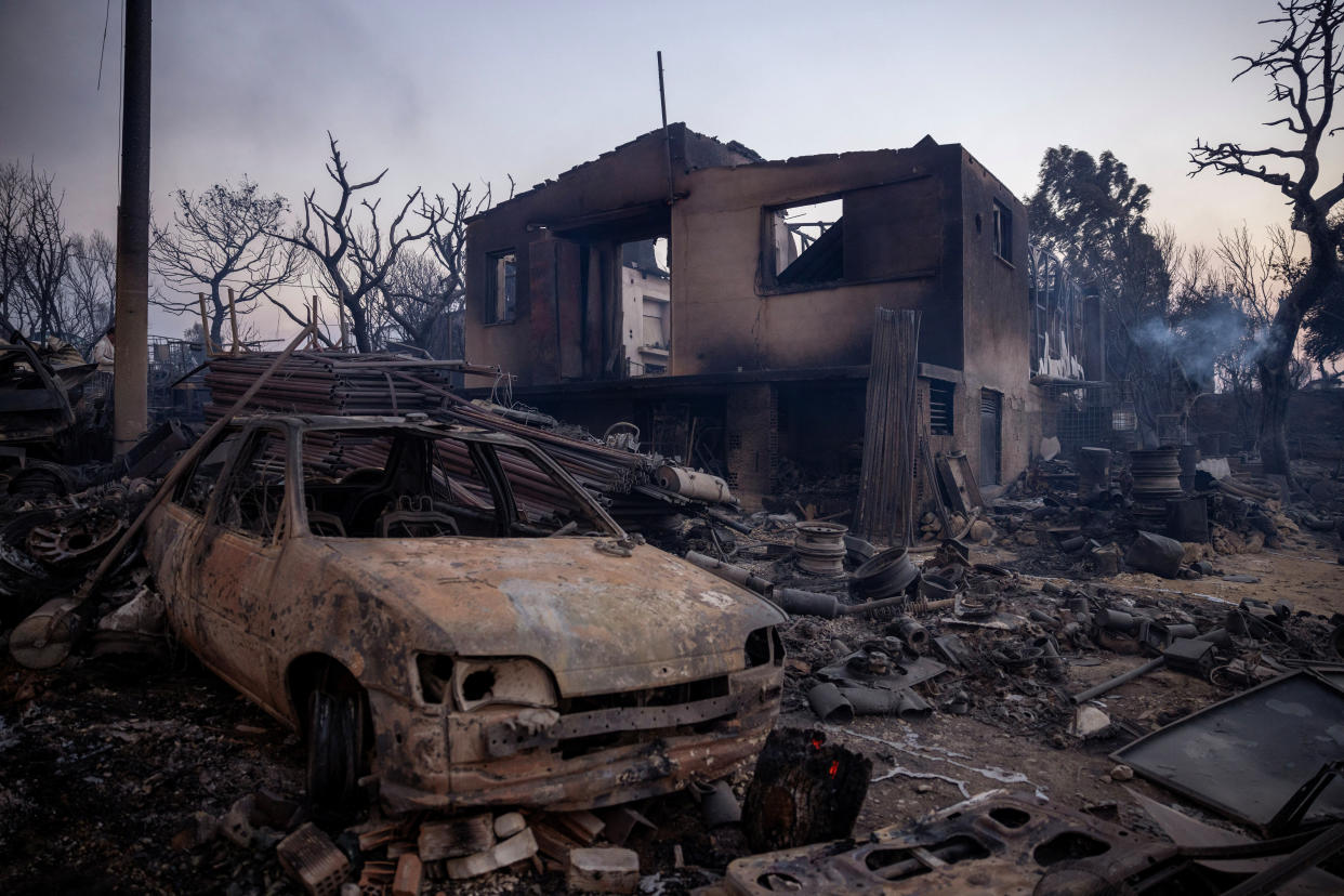 Wreckage from a wildfire smolders in Mandra, Greece