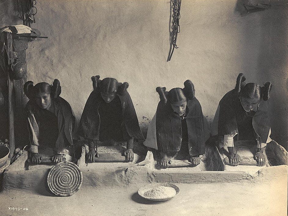 Photo shows four young Hopi Indian women grinding grain.