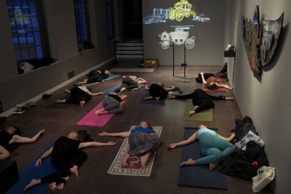 People take a yoga class at the Amsterdam Museum in Amsterdam, Wednesday, Jan. 19, 2022, as Dutch museums, theaters and concert halls played host Wednesday to businesses that are allowed to open to customers as a protest against their own continuing lockdown closures. (AP Photo/Peter Dejong)