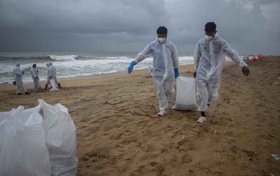 Sri Lankan navy soldiers carry sacks full of plastic debris washed ashore from fire damaged container ship MV X-Press Pearl at Kapungoda, on the outskirts of Colombo, Sri Lanka. Monday, June 14, 2021. (AP Photo/Eranga Jayawardena)