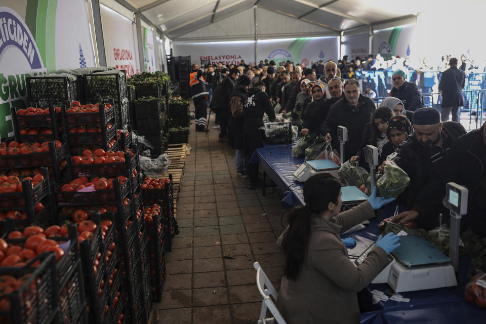 In this Sunday, Feb. 17, 2019 photo, shoppers wait in line to buy groceries at a government-run market selling spinach, tomatoes and peppers at discounted prices in an Istanbul neighbourhood. Turkey's President Recep Tayyip Erdogan's government has set up dozens of these temporary stalls in Turkey's largest cities in a bid to mitigate the effects of soaring food prices that have stung households. The move comes just over a month before Erdogan faces local elections on March 31, when runaway prices and an economic downturn could cost his ruling party some key municipal seats. (AP Photo/Emrah Gurel)