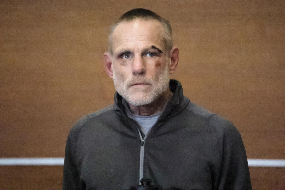 Peter Simon, with several visible facial lacerations, is arraigned in Waltham District Court, Thursday, Dec. 7, 2023. Simon is accused of crashing into a police officer and a utility employee at a work site, killing them, then pulling a knife on another officer before stealing his cruiser and crashing, law enforcement officials said. (Lane Turner/The Boston Globe via AP, Pool)