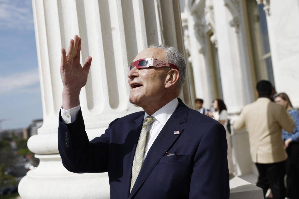 Senate Majority Leader Chuck Schumer uses eclipse viewing glasses to look up at the partial solar eclipse from his office balcony at the U.S. Capitol Building on April 8, 2024. / Credit: Anna Moneymaker/ Getty Images