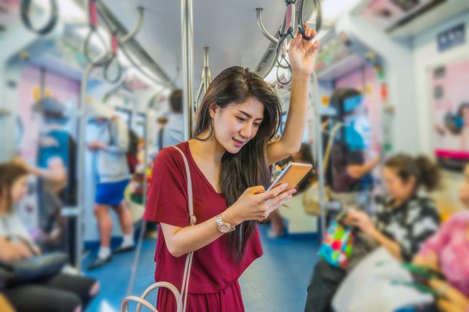 A woman reads her phone while riding public transit