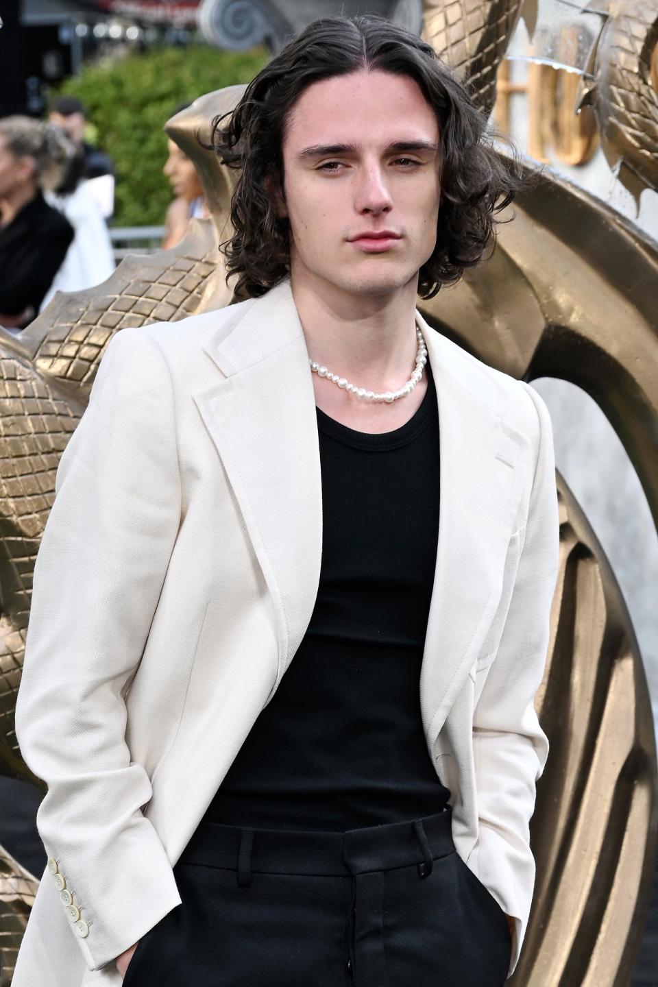 Harry Collett in a white jacket, black pants, and black shirt at the UK premiere of 