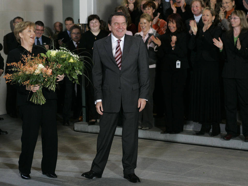 File - In this Tuesday, Nov. 22, 2005 file photo, former German Chancellor Gerhard Schroeder, right, is about to leave his offices in front of the staff of his chancellery after newly elected Chancellor Angela Merkel, left, took over his offices in Berlin. Angela Merkel will leave office in the coming months with her popularity intact, despite her party’s dismal election result. (AP Photo/Herbert Knosowski, File)