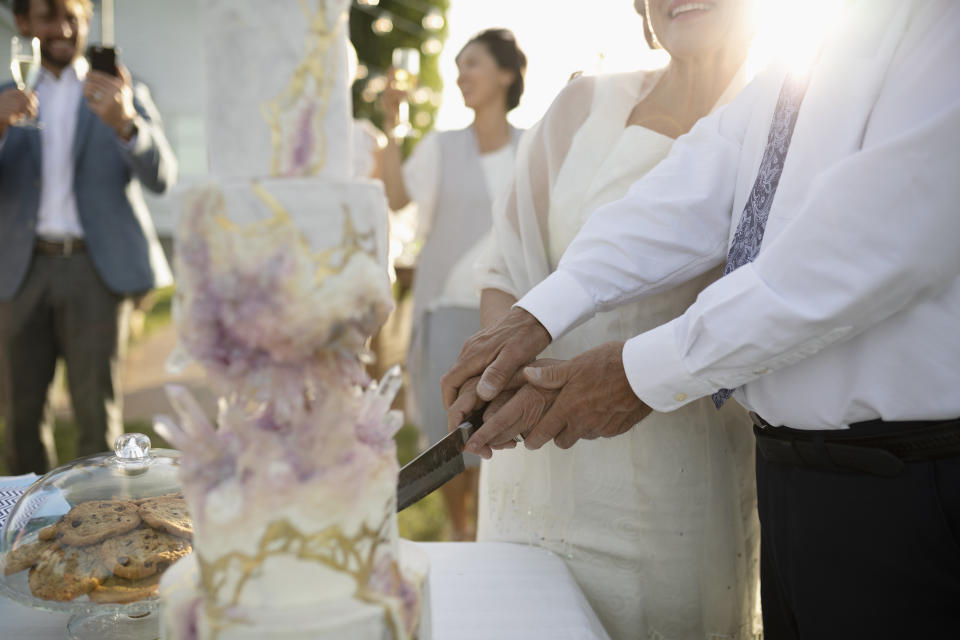 Senior bride and groom cutting wedding cake