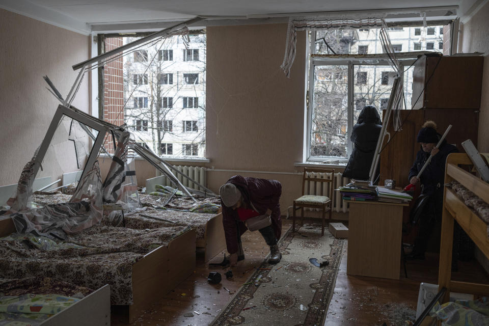 Women clear a broken glass at a kindergarten bedroom after a Russian rocket attack at a residential neighbourhood in Kyiv, Ukraine, Wednesday, Dec. 13, 2023. (AP Photo/Evgeniy Maloletka)