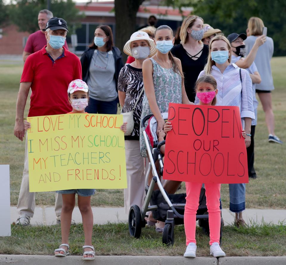 Diana Mejia, left, and Anna Sofiya Iskra, both 8, join their mothers, Olga Mejia, second right, and Olena Iskra, far right, at a demonstration  Aug. 23 after the Mequon-Thiensville School District in Wisconsin decided to keep schools closed in the fall.