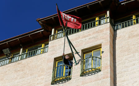 A staff fixes the flag of Temporary International Presence in Hebron (TIPH) at its headquarters in Hebron, in the Israeli-occupied West Bank January 29, 2019. REUTERS/Mussa Qawasma